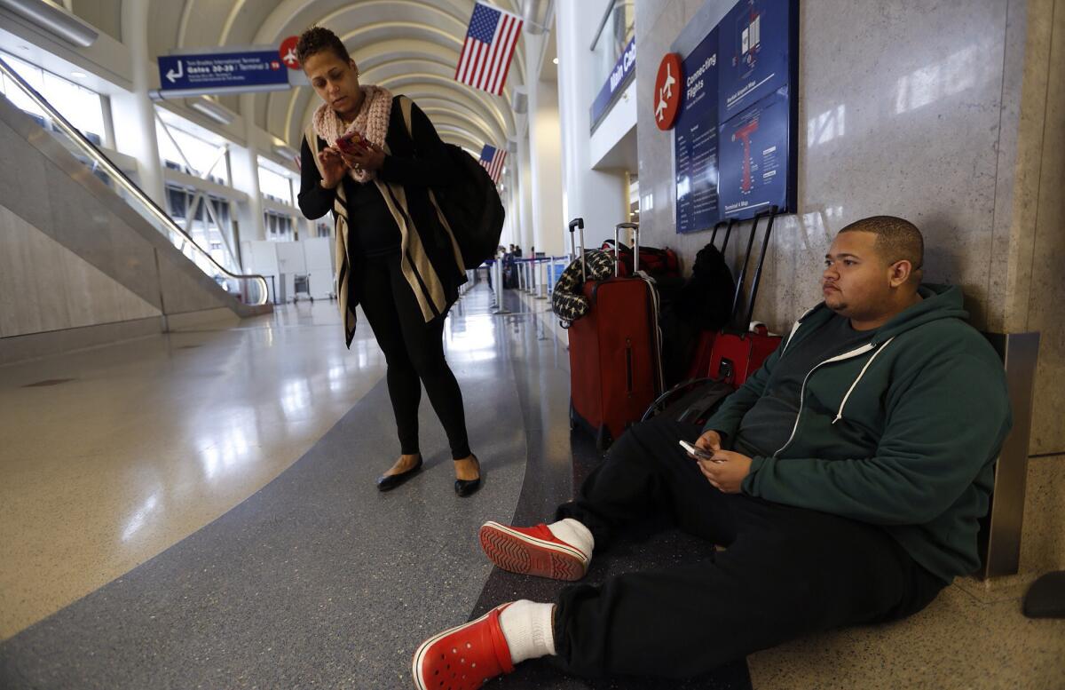 Joseph Goncalves and his mother, Tanya Cabral, make calls looking for a place to stay after their American Airlines flight from Los Angeles home to Boston was canceled on Jan. 26 because of a snowstorm on the East Coast.