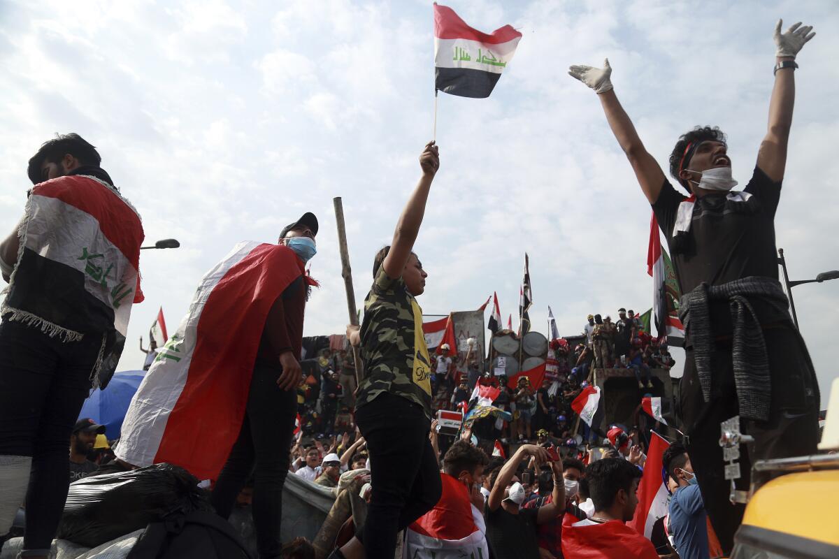 Antigovernment protesters stand Nov. 3  on barriers that Iraqi security forces set up to close a bridge in Baghdad.