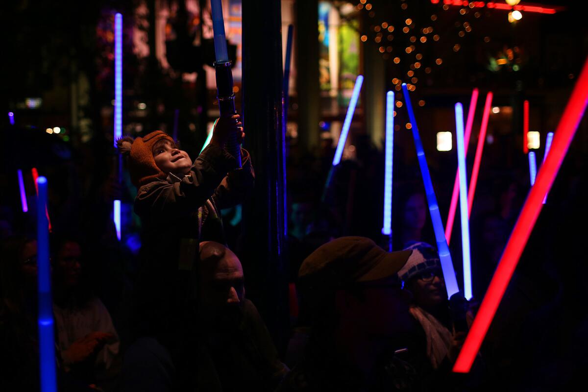 ANAHEIM, CA. --WEDNESDAY, DECEMBER 28, 2016 -- Jay Cotton Jr., 4, of Whittier, sits on his father Jay Cotton's shoulders for a lightsaber vigil for Star Wars actress Carrie Fisher held in Downtown Disney, which drew about 100 people to honor her memory. Fisher died days after suffering a cardiac event during a transatlantic flight. ( Rick Loomis / Los Angeles Times )