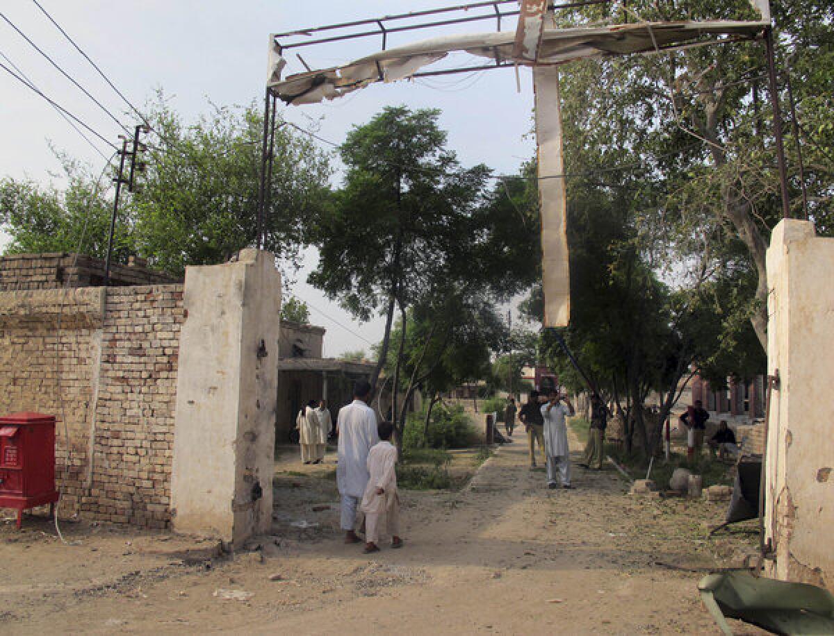 Police investigators and passersby inspect the bombed-out entrance to a prison in remote Dera Ismail Khan, in Pakistan's restive northwest. Dozens of Taliban militants attacked the prison late Monday and freed nearly 250 prisoners, many of them Al Qaeda-allied militants. It was the third massive breakout of Islamic extremists in a week.