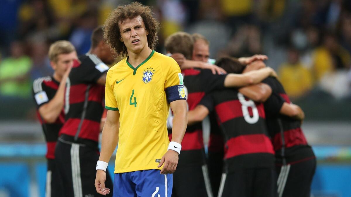 Brazil defender David Luiz reacts as Germany celebrates an early goal during its 7-1 World Cup semifinal victory Tuesday. Before its blowout loss to Germany, Brazil's last World Cup loss on home soil occurred in 1950.