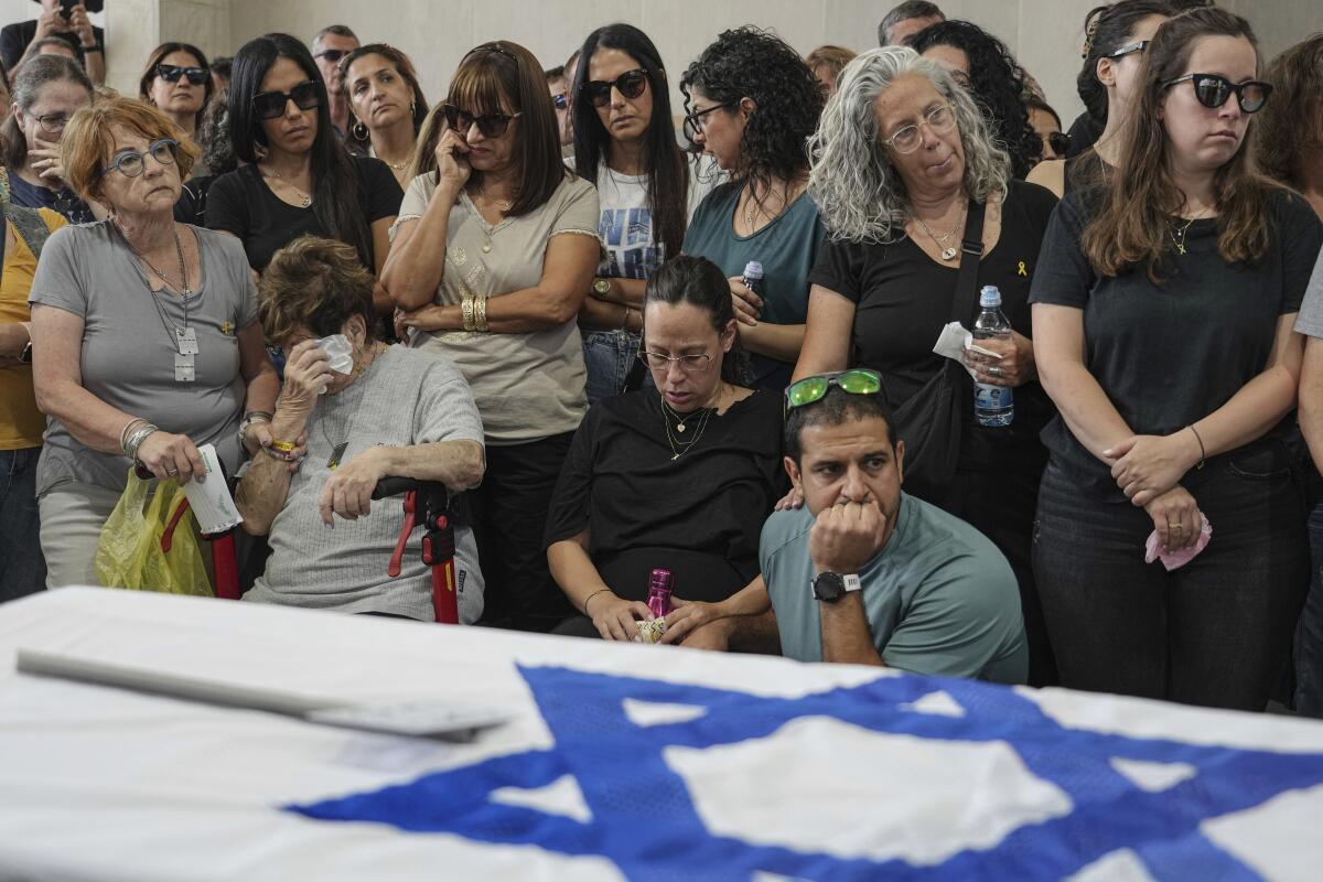 Mourners attending a funeral stand behind a coffin draped with the Israeli flag.