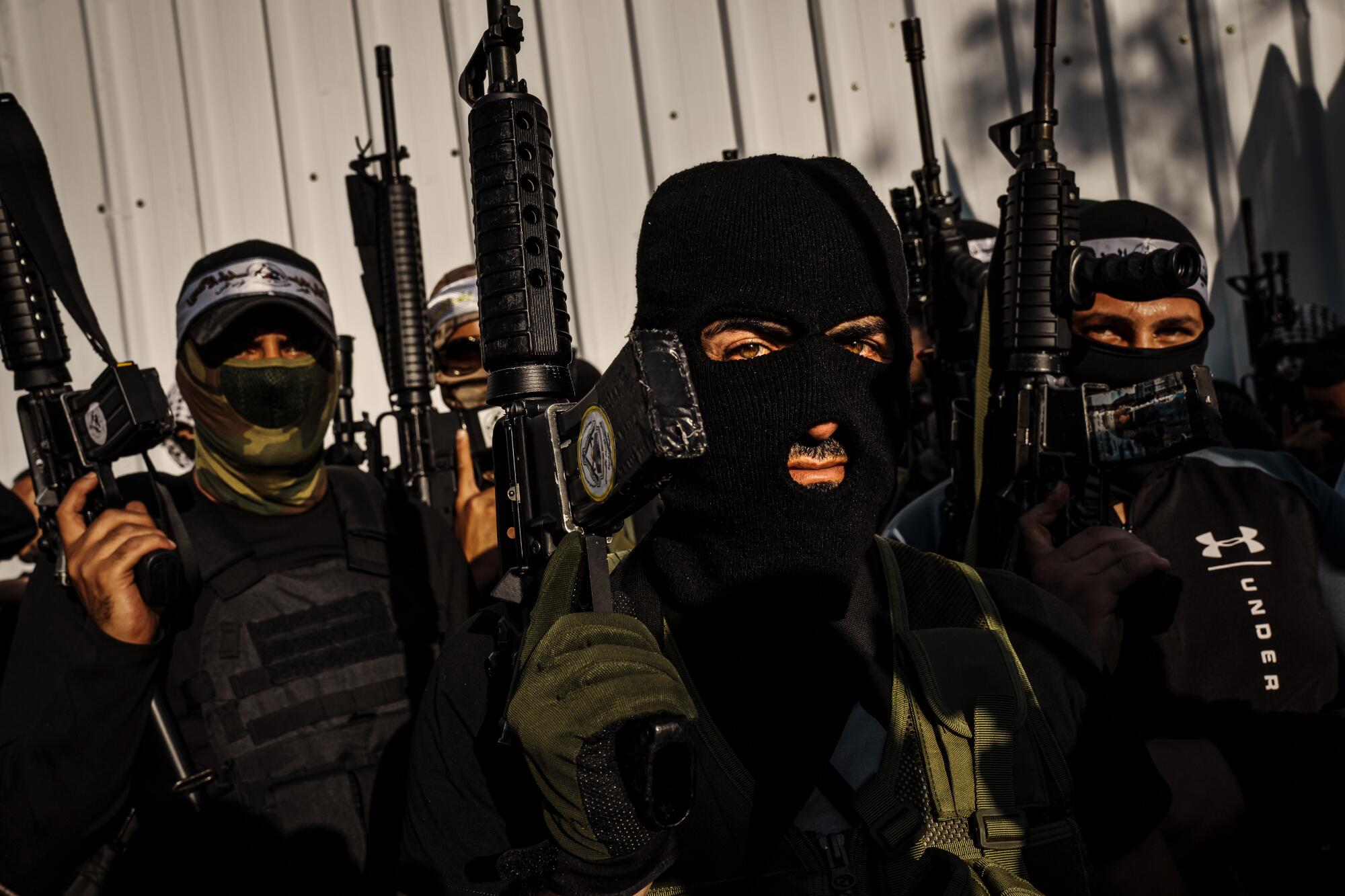 Men hold automatic weapons, their faces hidden behind masks. 