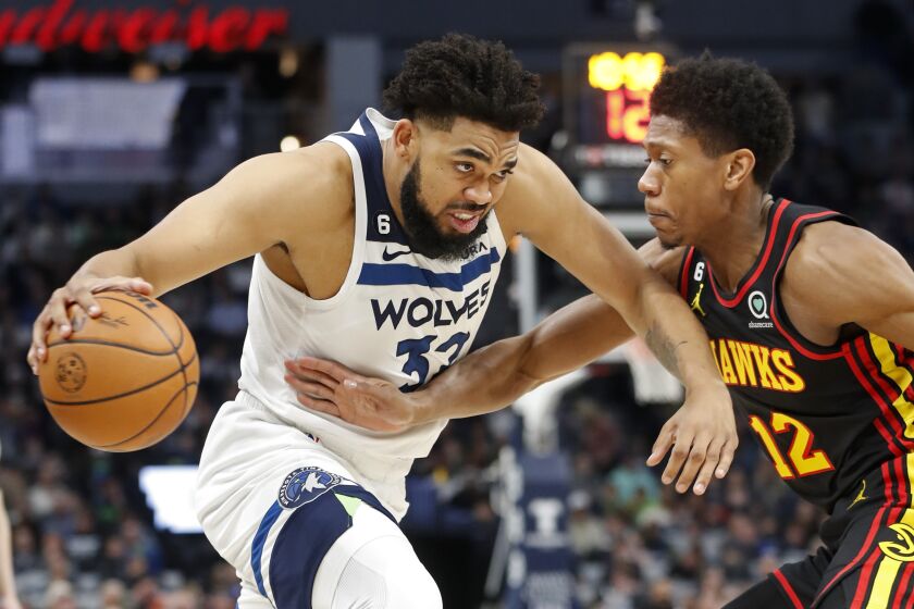 Minnesota Timberwolves center Karl-Anthony Towns (32) works past Atlanta Hawks forward De'Andre Hunter (12) in the first quarter of an NBA basketball game Wednesday, March 22, 2023, in Minneapolis. (AP Photo/Bruce Kluckhohn)
