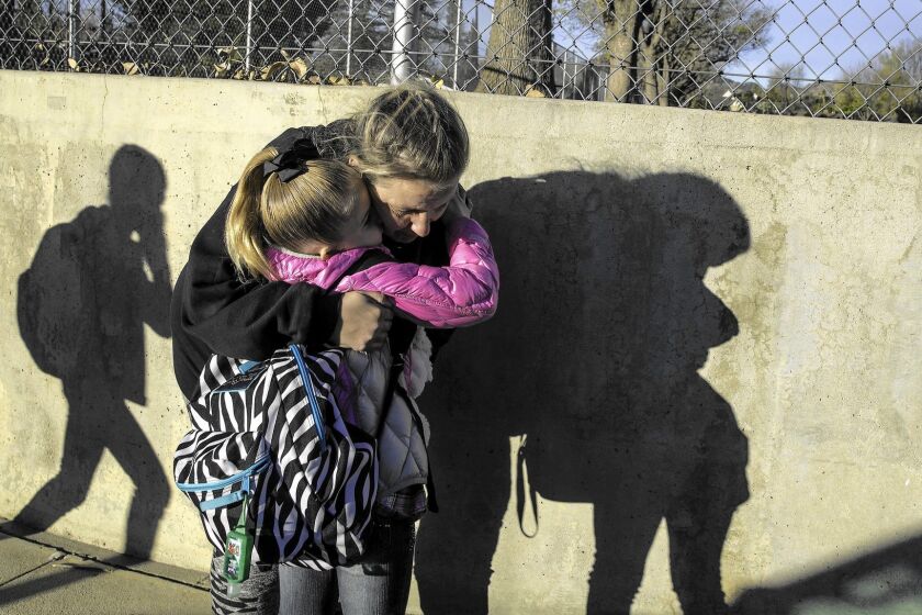 Leah Hooper, 8, hugs her mother, Tiffany, as she is dropped off at Germain Street Elementary School.