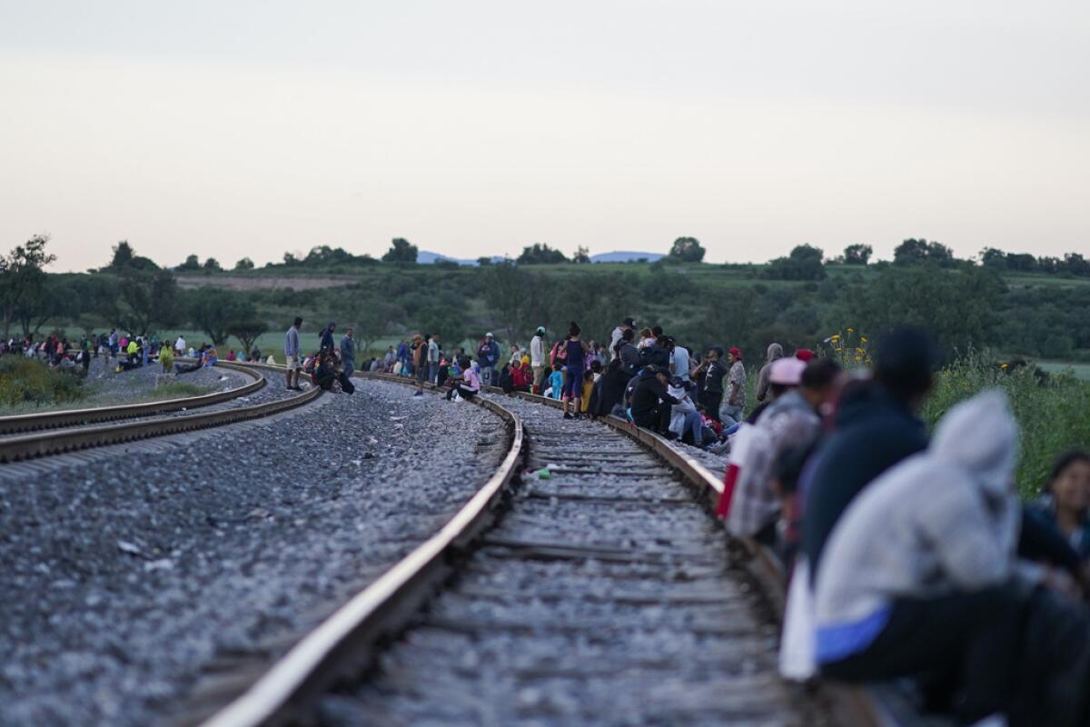 Migrantes esperan a lo largo de las vías.