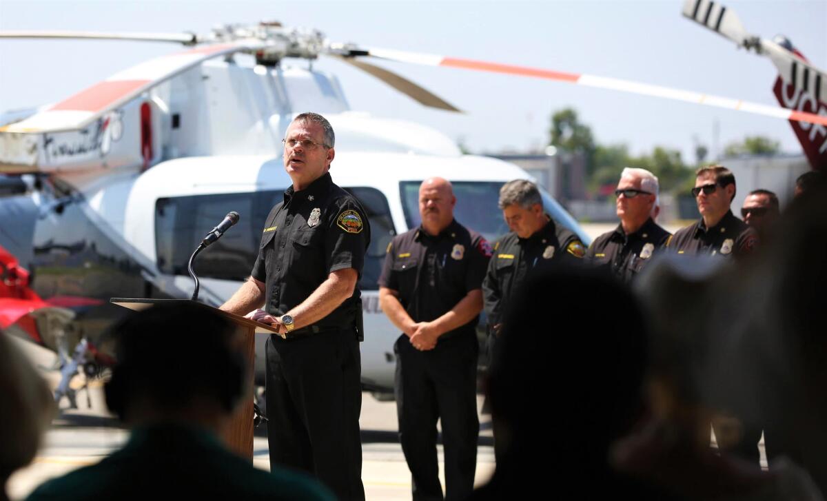 OCFA Chief Brian Fennessy speaks to a crowd near a helicopter.