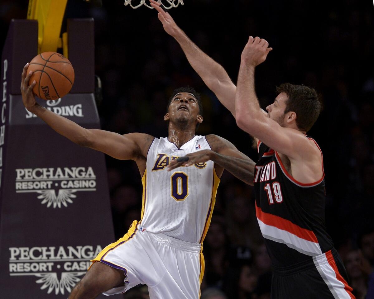 Lakers forward Nick Young, left, puts up a shot in front of Portland Trail Blazers center Joel Freeland during the first half of Sunday's game at Staples Center.