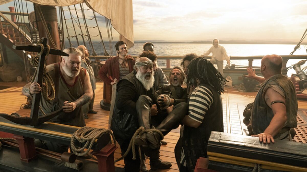 A group of men on the deck of a pirate ship prepare to throw someone overboard
