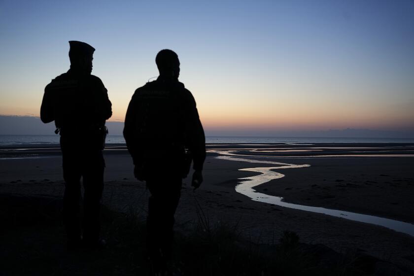 Policemen guard the area during the sun is about to rise over Omaha Beach near Colleville-sur-Mer Normandy, Thursday, June 6, 2024. World War II veterans from across the United States as well as Britain and Canada are in Normandy this week to mark 80 years since the D-Day landings that helped lead to Hitler's defeat. (AP Photo/Laurent Cipriani)
