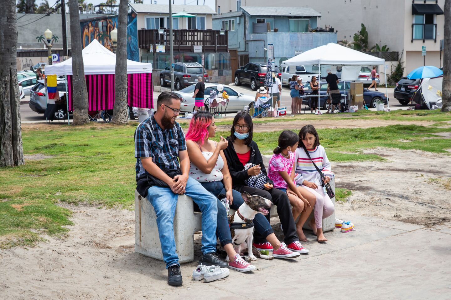 Steven and Yani Himenez sit with their three daughters and dog Briote at Ocean Beach's Veterans Plaza.