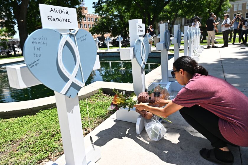 Uvalde, Texas May 26, 2022- A mourner places flowers at a memorial for the victims of a mass shooting in Uvalde, Texas. Nineteen students and two teachers died when a gunman opened fire in a classroom Tuesday. (Wally Skalij/Los Angeles Times)