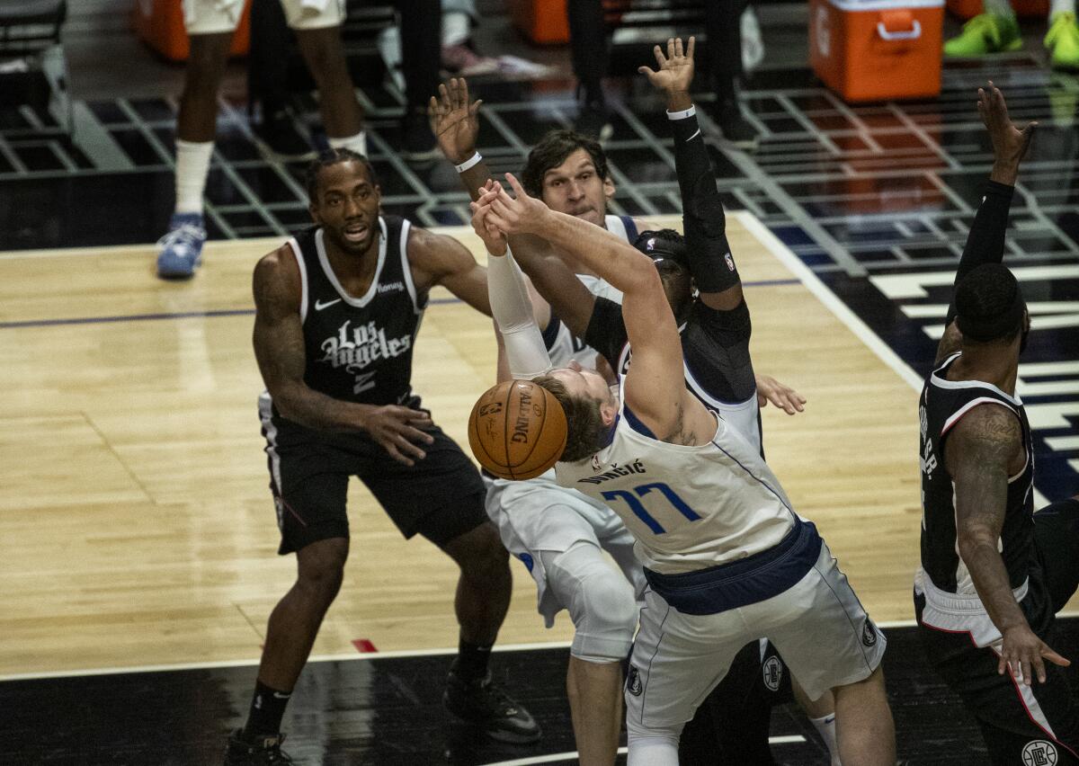 Clippers guard Reggie Jackson and forward Kawhi Leonard, left, force a turnover by Dallas Mavericks guard Luka Doncic.
