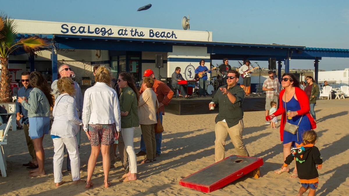 Visitors play a game with sandbags near a stage at SeaLegs at the Beach. Starting July 4, SeaLegs will have a nighttime music venue called SeaLegs Live.