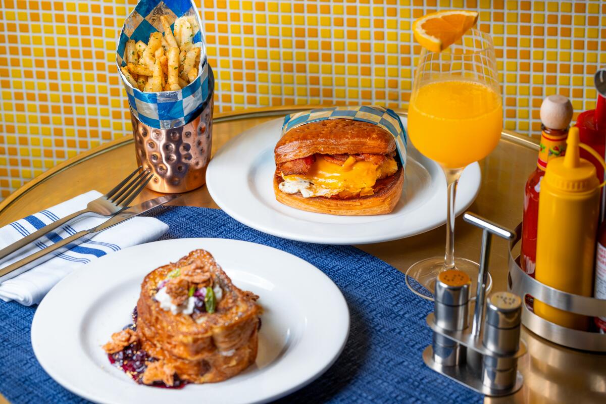 French fries, a sandwich in a bun, French toast and a mimosa