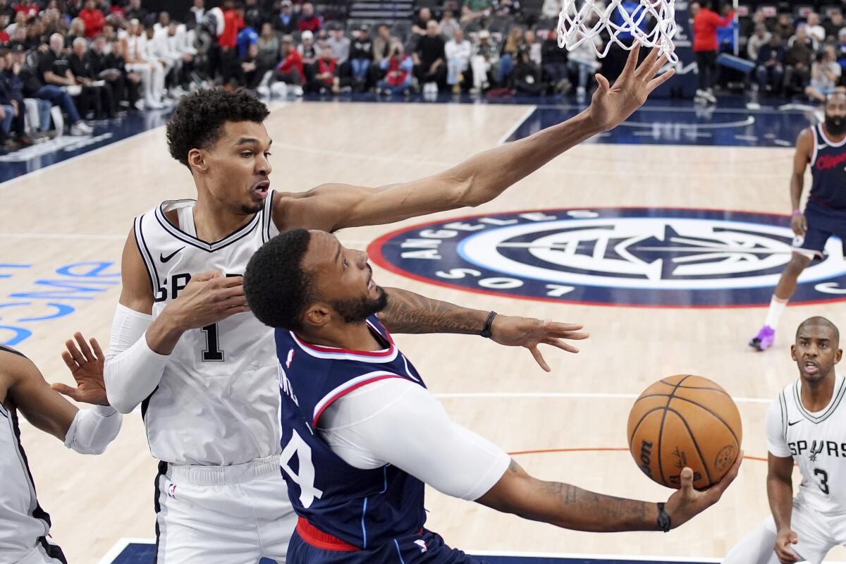 Clippers guard Norman Powell, bottom, shoots in front of San Antonio Spurs center Victor Wembanyama at Intuit Dome.