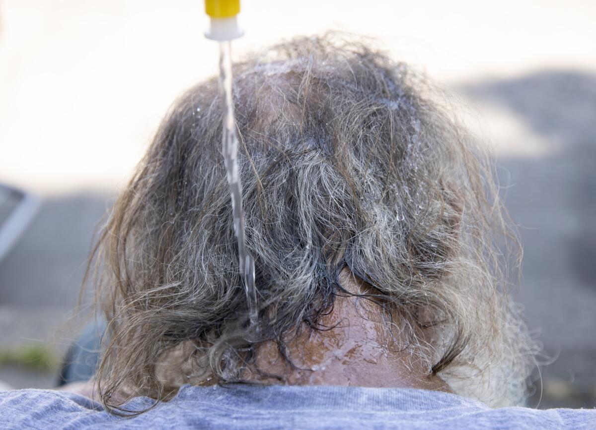 Water is squeezed onto a man's head during a heat wave.