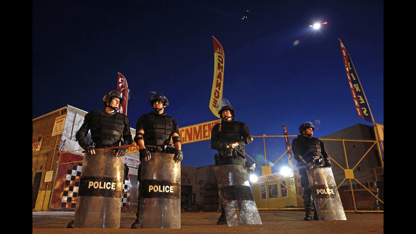 Members of the Prince George's County, Md., police force stand guard as curfew approaches in Baltimore.