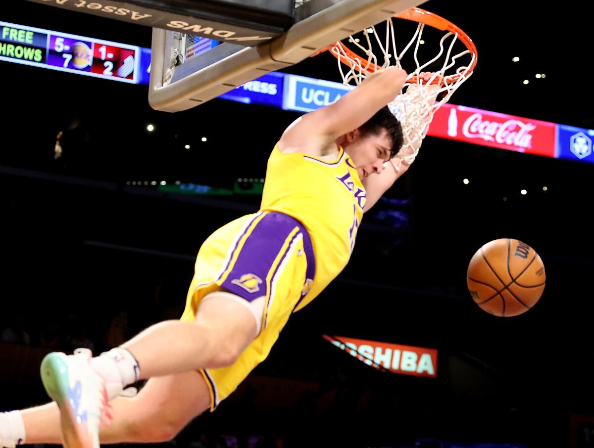 Lakers guard Austin Reaves hangs on the rim after dunking the ball.