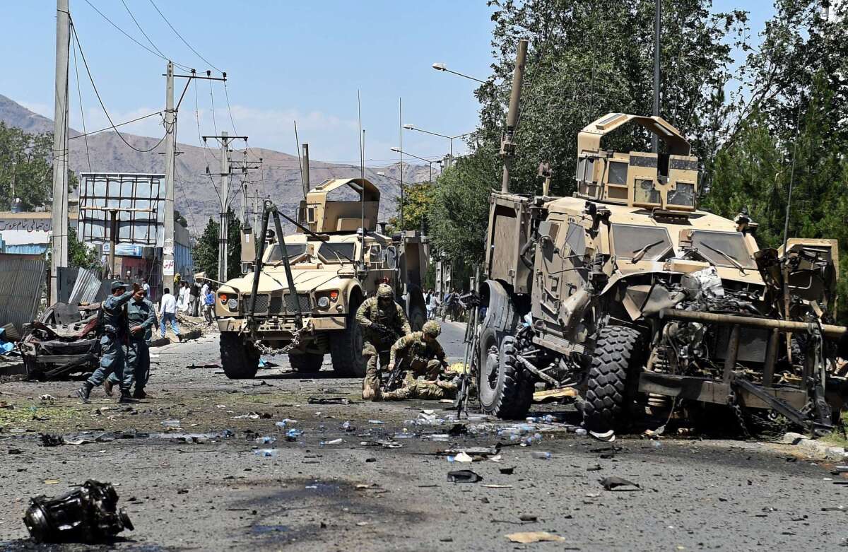 An NATO soldier helps a colleague who was injured in a suicide car bomb attack that targeted foreign military vehicles in the Afghan capital Kabul on June 30,2015.
