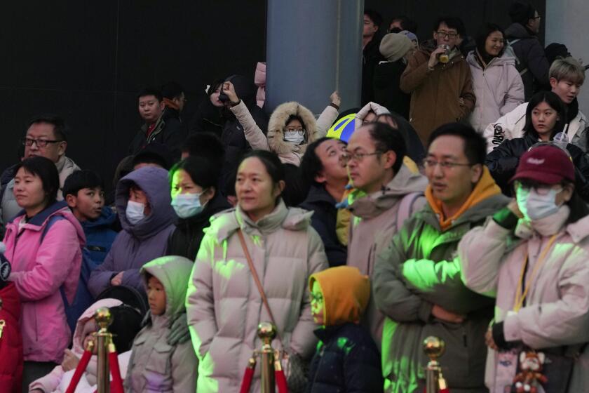 A child, center back, reacts in a crowd at a shopping mall in Beijing on Dec. 30, 2023. China’s population dropped by 2 million people in 2023 in the second straight annual drop as births fell and deaths jumped. (AP Photo/Ng Han Guan)