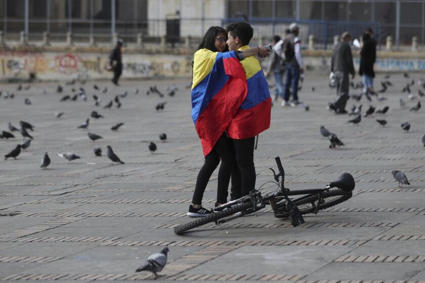 A young couple, wrapped with the Colombian flag, attend an anti-government protest at the Bolivar square in Bogota, Colombia, Monday, May 24, 2021. (AP Photo/Fernando Vergara)