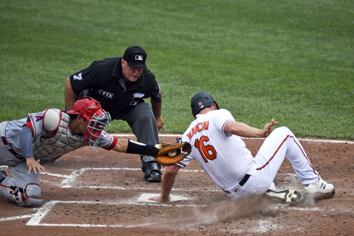 Baltimore Orioles' Trey Mancini (16) is tagged out at home plate by Los Angeles Angels catcher Kurt Suzuki.