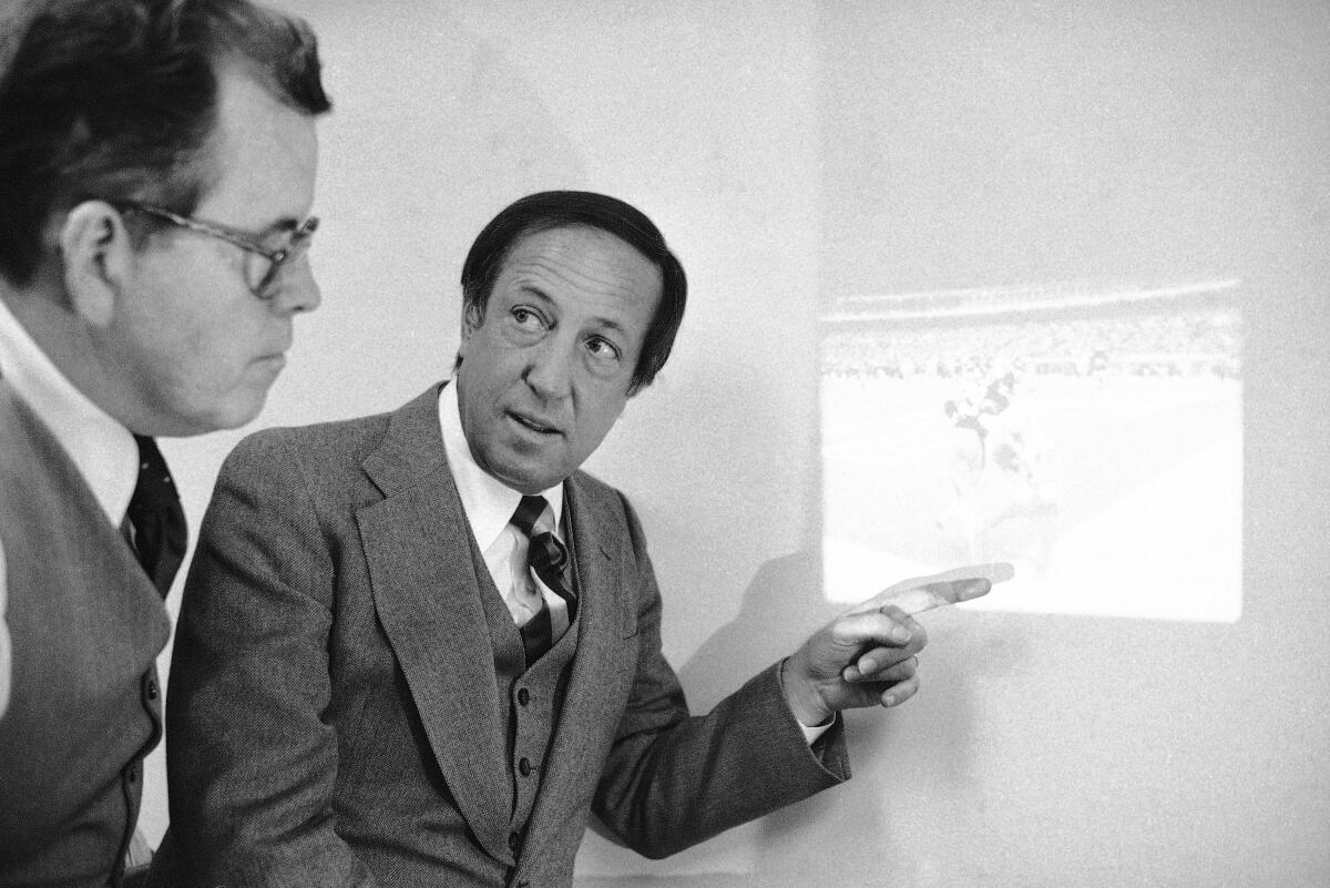 FILE - Art McNally, left, supervisor of National Football League officials, and NFL Commissioner Pete Rozelle discuss a photo on Jan. 7, 1980, at the NFL offices in New York, of a controversial play involving the touchdown disallowed for the Houston Oilers in their American Conference playoff game for the title with the Pittsburgh Steelers. McNally, the former official who helped modernize the practice when he oversaw the operation from the league office, will become the first on-field official inducted into the Pro Football Hall of Fame on Saturday night, Aug. 6, 2022. (AP Photo//David Pickoff, File)