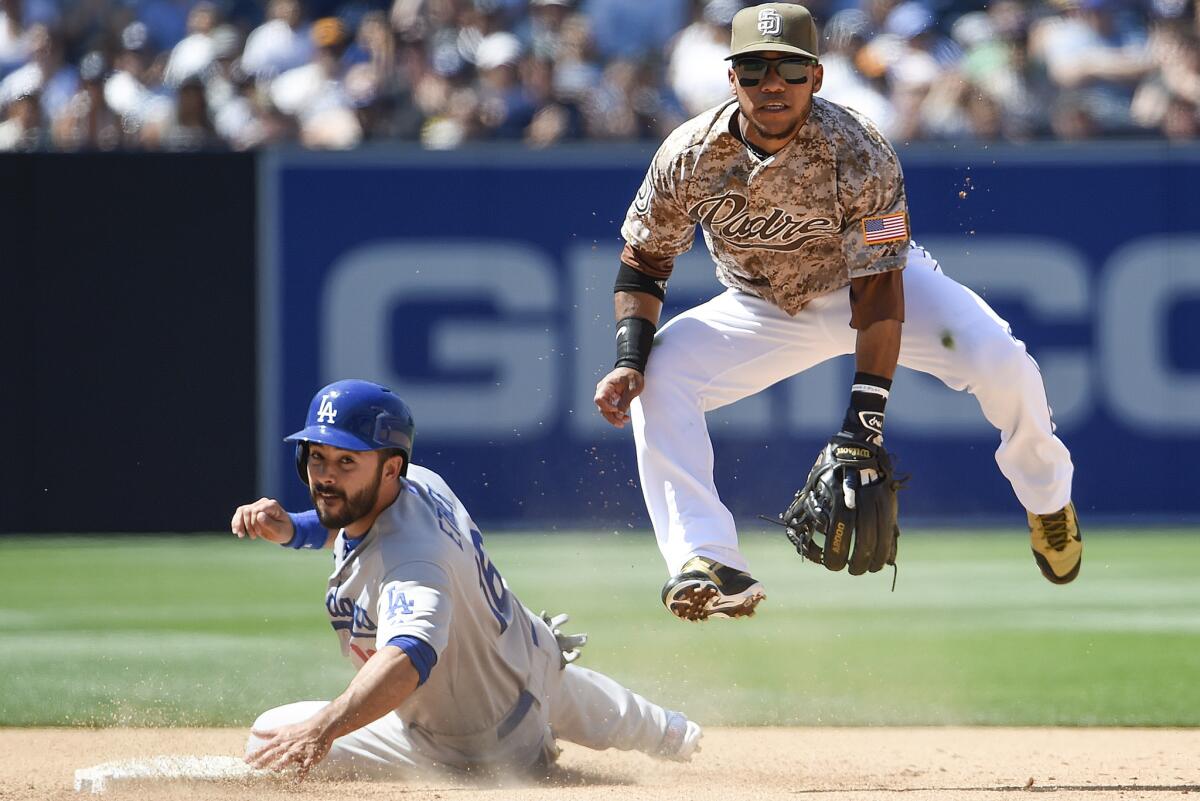 Alexi Amarista, de San Diego, salta ante la barrida de Andre Ethier, de Dodgers, que buscaba evitar el out.