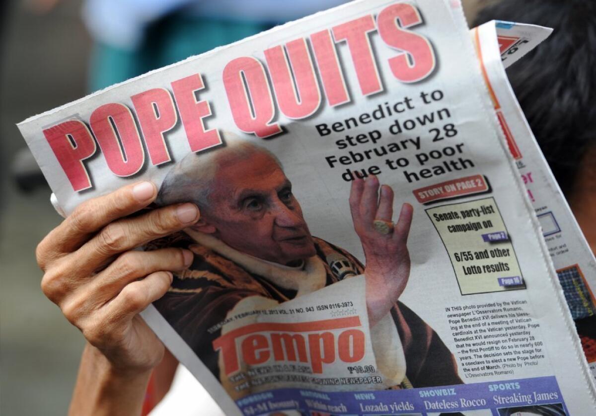 A vendor reads a newspaper featuring the story of the resignation of Pope Benedict XVI near a church in Manila.