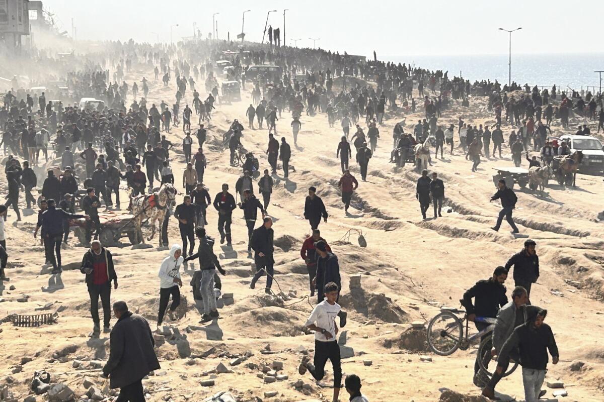 Hundreds of Palestinians wait for humanitarian aid on a beach in Gaza City.
