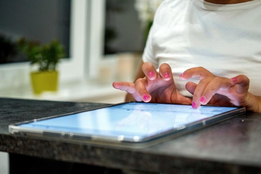 An elementary school student sits at a tablet computer typing.