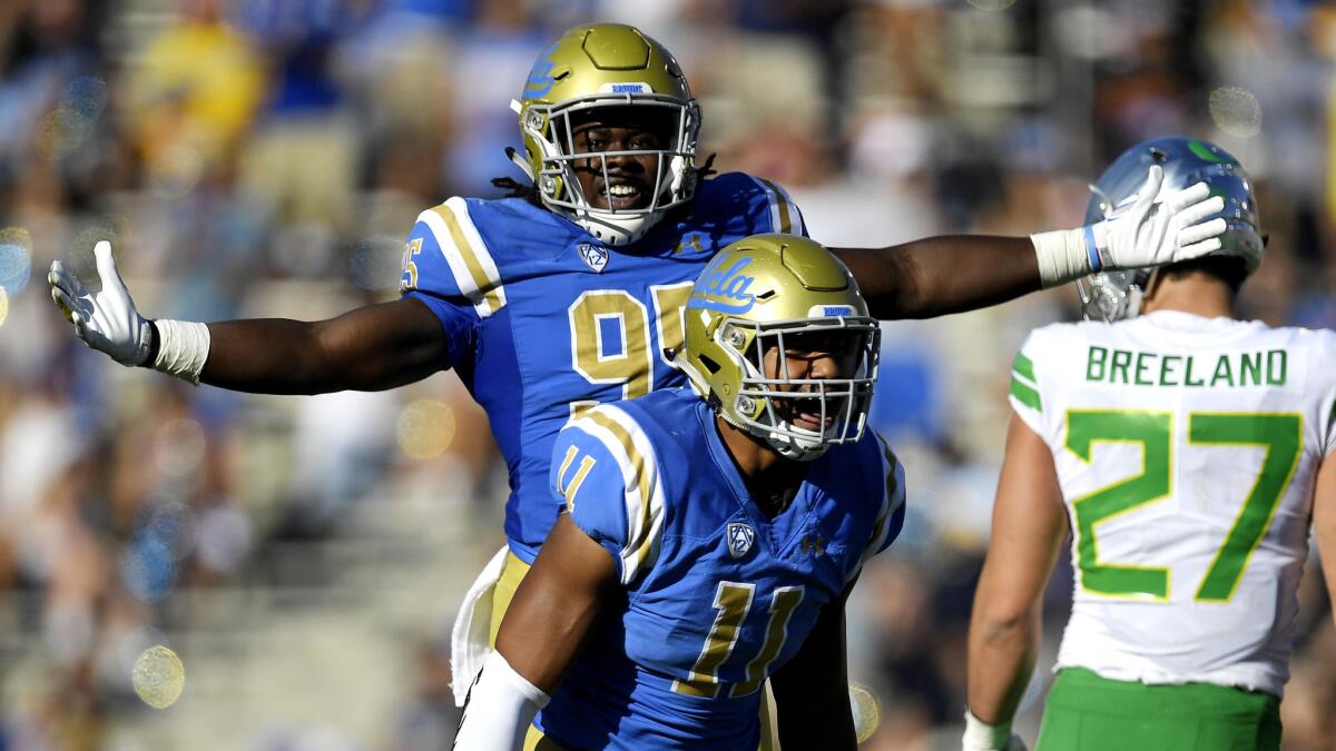 UCLA defensive linemen Marcus Moore (95) and Keisean Lucier-South (11) celebrate after forcing a turnover by Oregon during the second half Saturday.