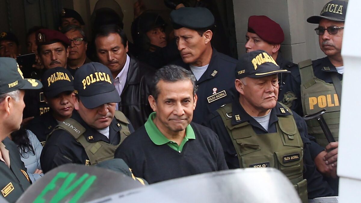 Former Peruvian President Ollanta Humala, center, leaves the Palace of Justice in Lima under heavy guard Thursday. He was ordered incarcerated while the government pursues criminal charges against him.