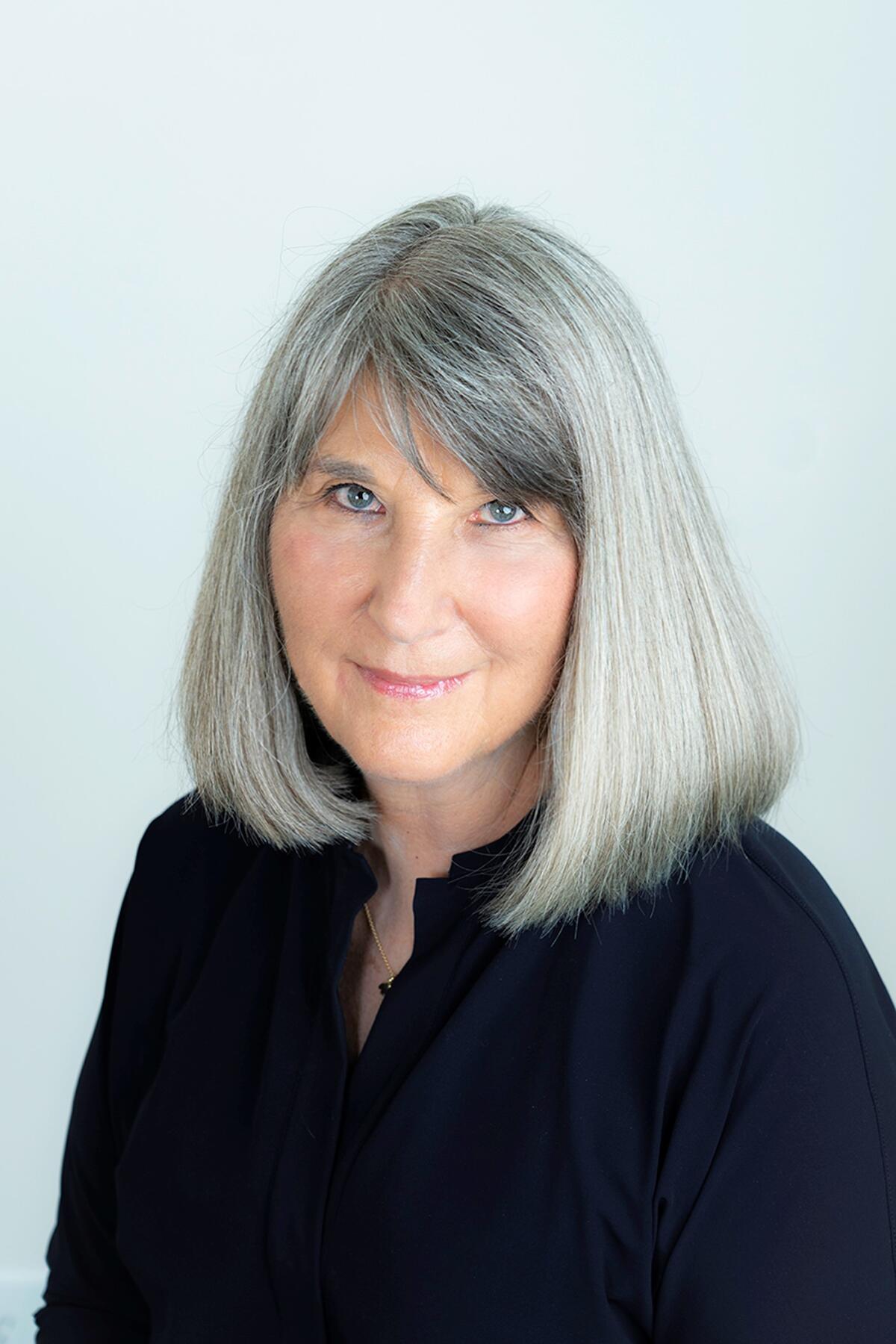 A woman with silver hair wearing a black dress sweater.