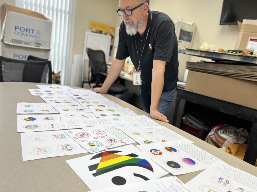 A man looks over Goodwill of Orange County's Pride & Ally button art submissions.