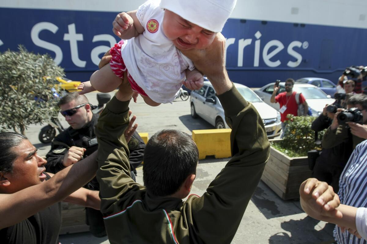 A man holds a baby over his head during an altercation with police at the Greek port of Piraeus on April 6.
