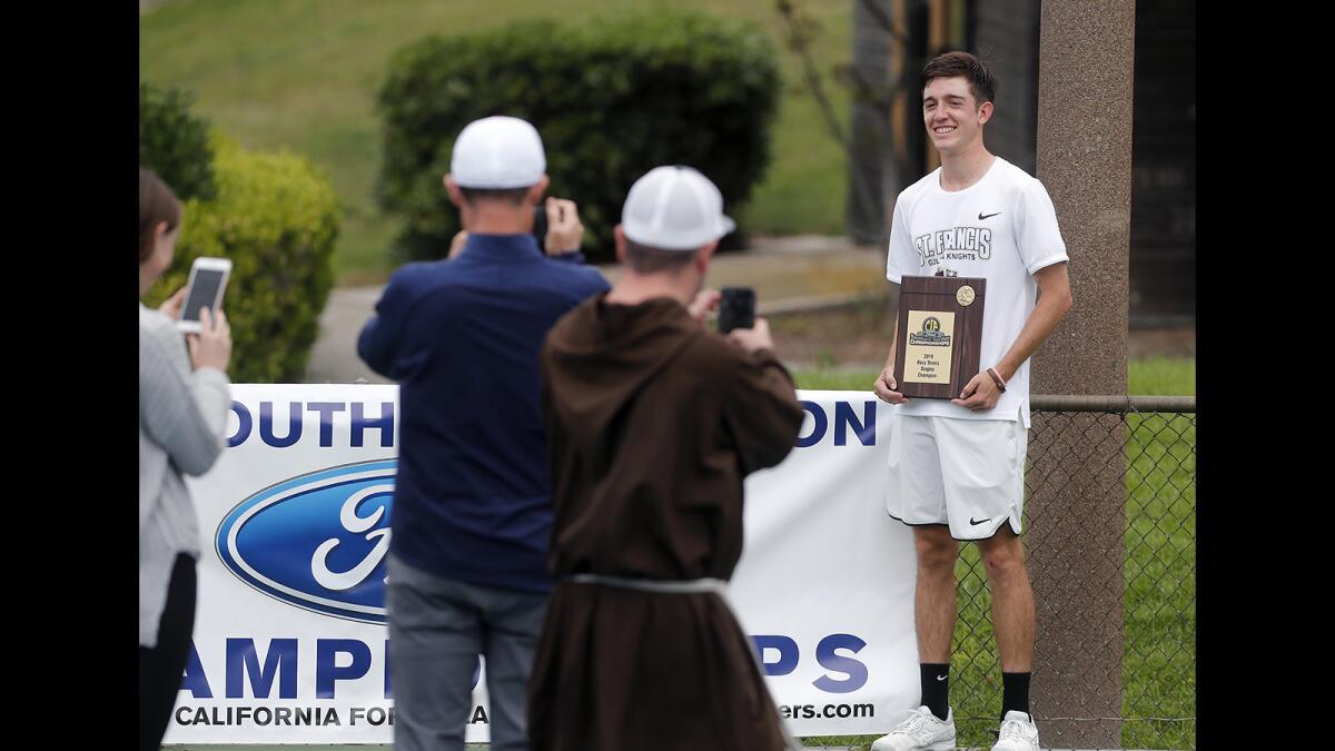 St. Francis' Ian Freer pose for photos with his CIF Southern Section Individuals singles tournament plaque on Thursday at Seal Beach Tennis Center.