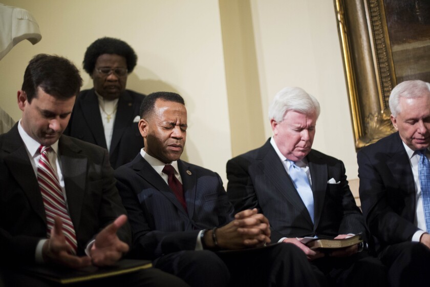 Fired Atlanta Fire Chief Kelvin Cochran, third from left, prays with supporters at a rally at the state Capitol.