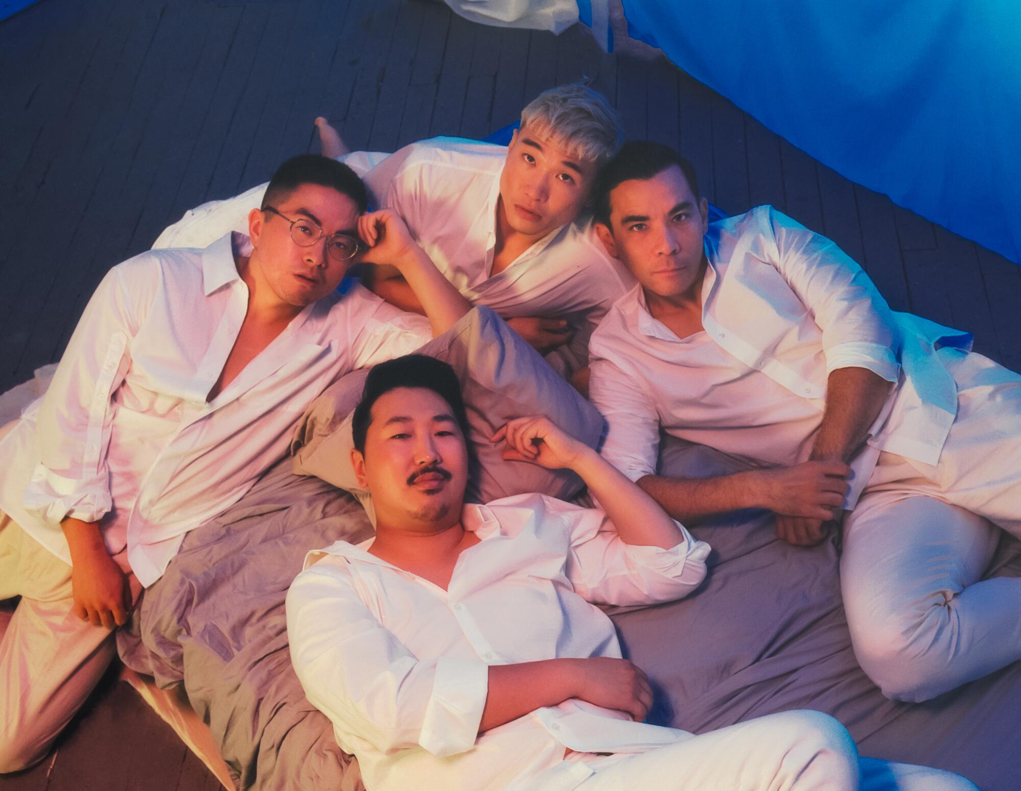 four men in white outfits lay on a bed