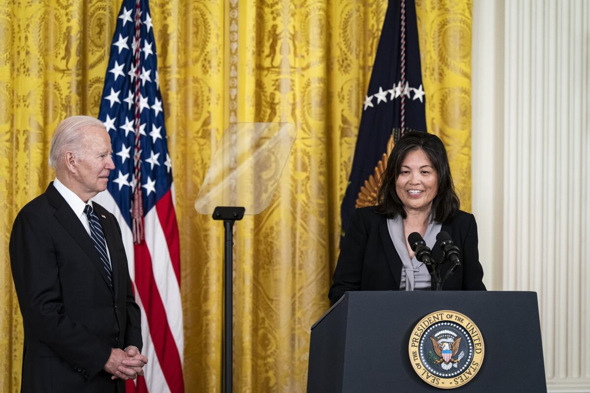 Julie Su stands next to President Biden in the East Room of the White House.