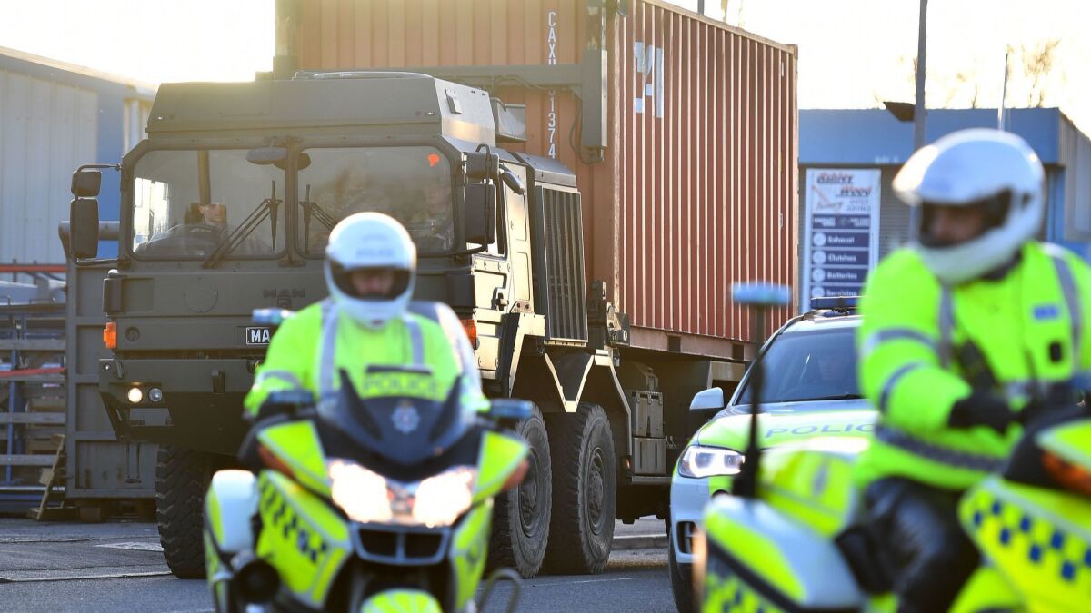 Motorcycle police escort a British army truck carrying the car of Sergei Skripal as it is driven from the Churchfields industrial estate in Salisbury.