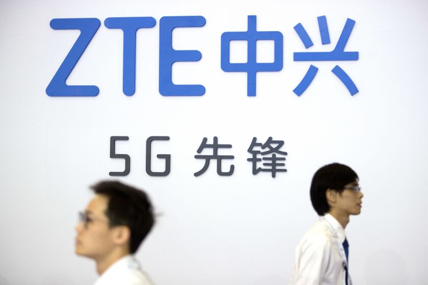 FILE - In this Sept. 26, 2018 file photo, visitors walk past a display from Chinese technology firm ZTE at the PT Expo in Beijing. The U.S. is banning the sale of communications equipment made by Chinese companies Huawei and ZTE and restricting the use of some China-made video surveillance systems, citing an “unacceptable risk” to national security. The 5-member Federal Communications Commission said Friday, Nov. 25, 2022 it has voted unanimously to adopt new rules that will block the importation or sale of certain technology products that pose security risks. (AP Photo/Mark Schiefelbein, file)