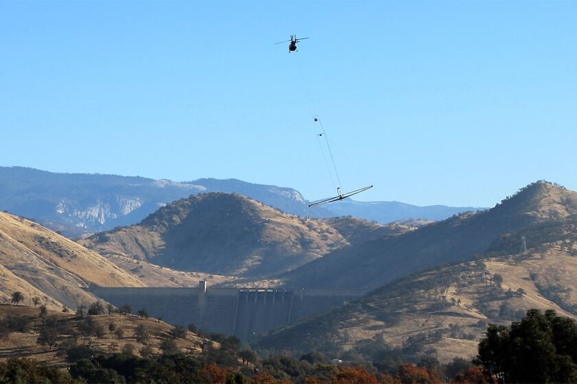 A helicopter flies near Pine Flat Dam towing an airborne electromagnetic system during a survey of the Kings River alluvial fan in December 2020. (Kings River Conservation District)