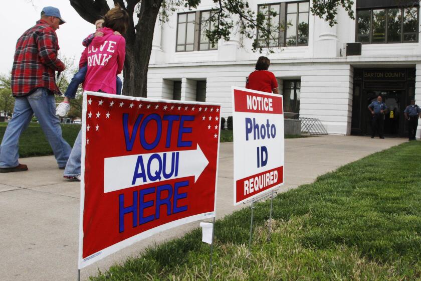 Signs notifying the need for photo ID's are located outside the Barton County Court House while polls are open for a city commission election in Great Bend, Kan., Tuesday, April 3, 2012. (AP Photo/Orlin Wagner)