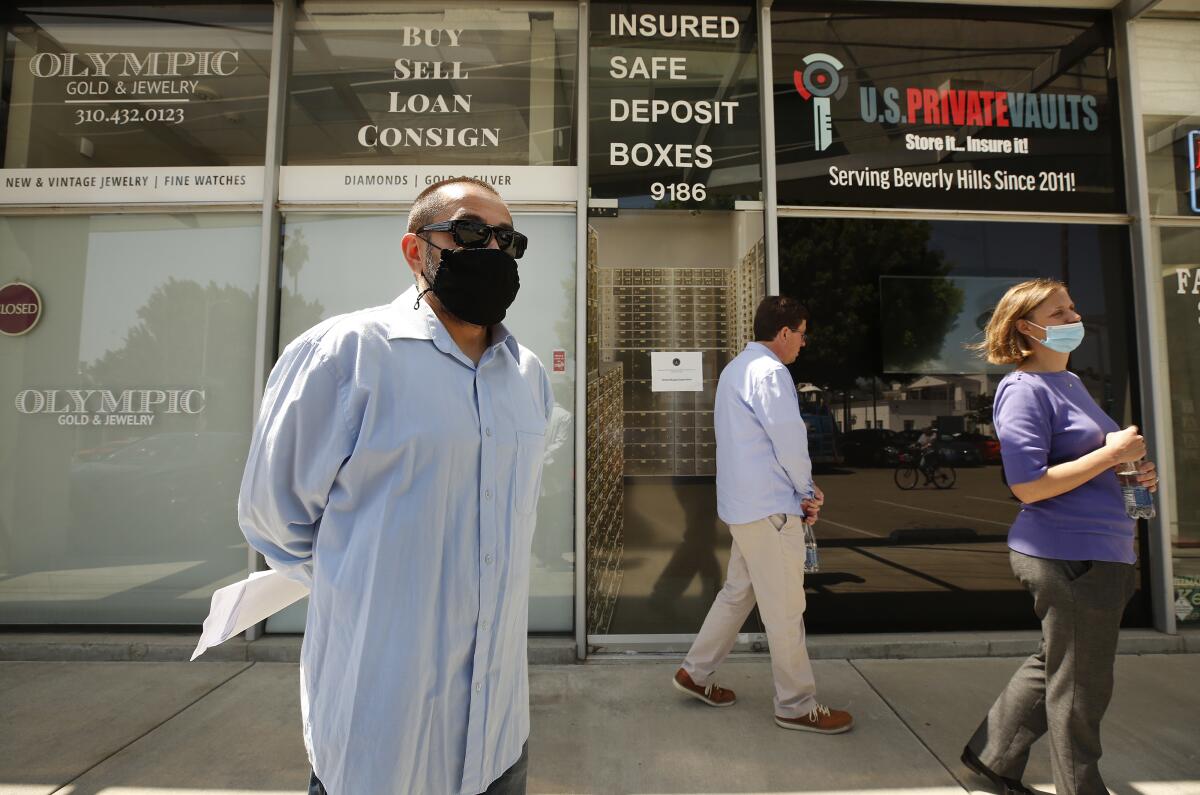 A masked man holding papers stands outside a store