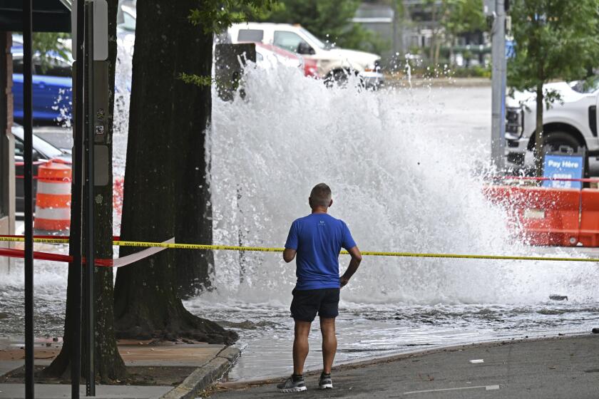 Joe Greene watches a water main break Saturday, June 1, 2024, in Atlanta. City officials were slowly repressuring the city's water system Saturday after corroding water pipes burst in downtown and Midtown, forcing many businesses and attractions to close and affecting water service in area homes. (Hyosub Shin/Atlanta Journal-Constitution via AP)