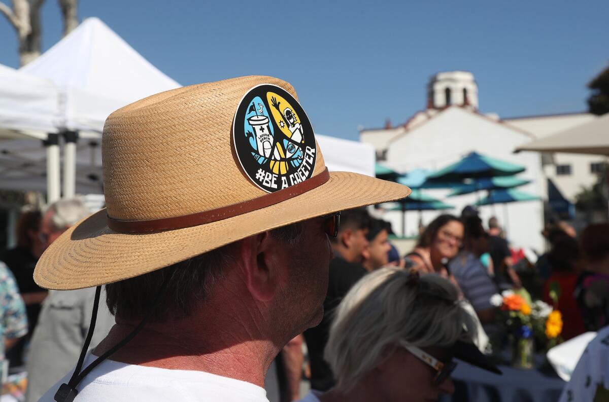 A guest wears a "#be a greeter" sun hat by local artist Steven "Sli Dawg" Chew.