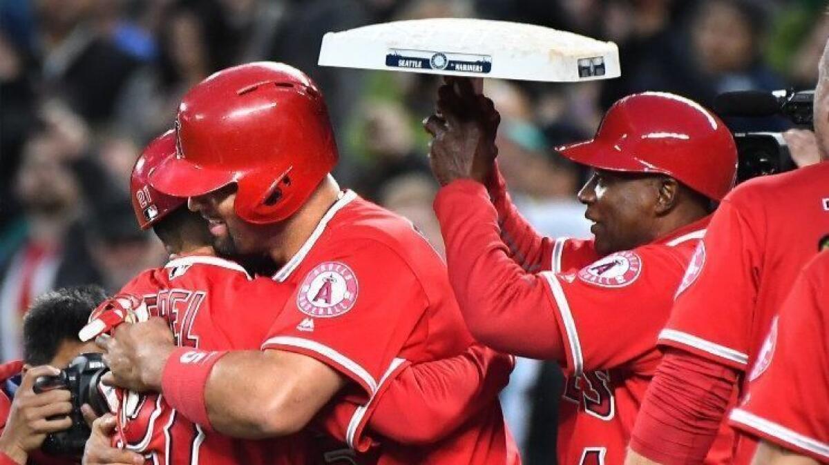 Angels first baseman Albert Pujols hugs his teammates after getting his 3,000th career hit during a game against the Mariners in Seattle on Friday.