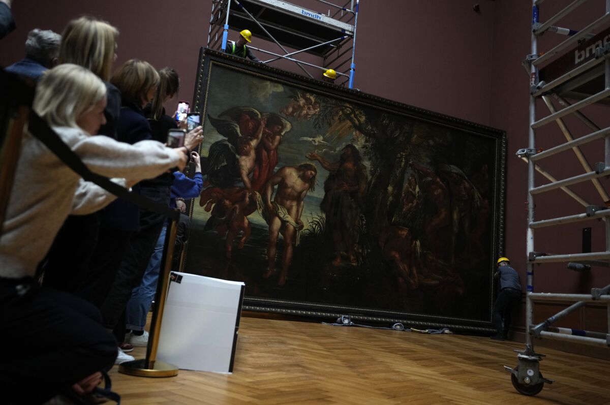 People take photos with their mobile phones as technicians and art handlers move the 'Baptism of Christ', by Baroque painter Peter Paul Rubens inside a gallery at the Royal Museum of Fine Arts Antwerp in Antwerp, Belgium, Tuesday, March 15, 2022. Moving a masterpiece is never easy, even more-so when it measures 4.11 by 6.75 meters (13.5 feet by 22.1 feet) and weighs 560 kilograms (1,225 pounds). The Rubens painting is the first to be moved back into its gallery hall after a decade long renovation of the museum which will open in September. (AP Photo/Virginia Mayo)